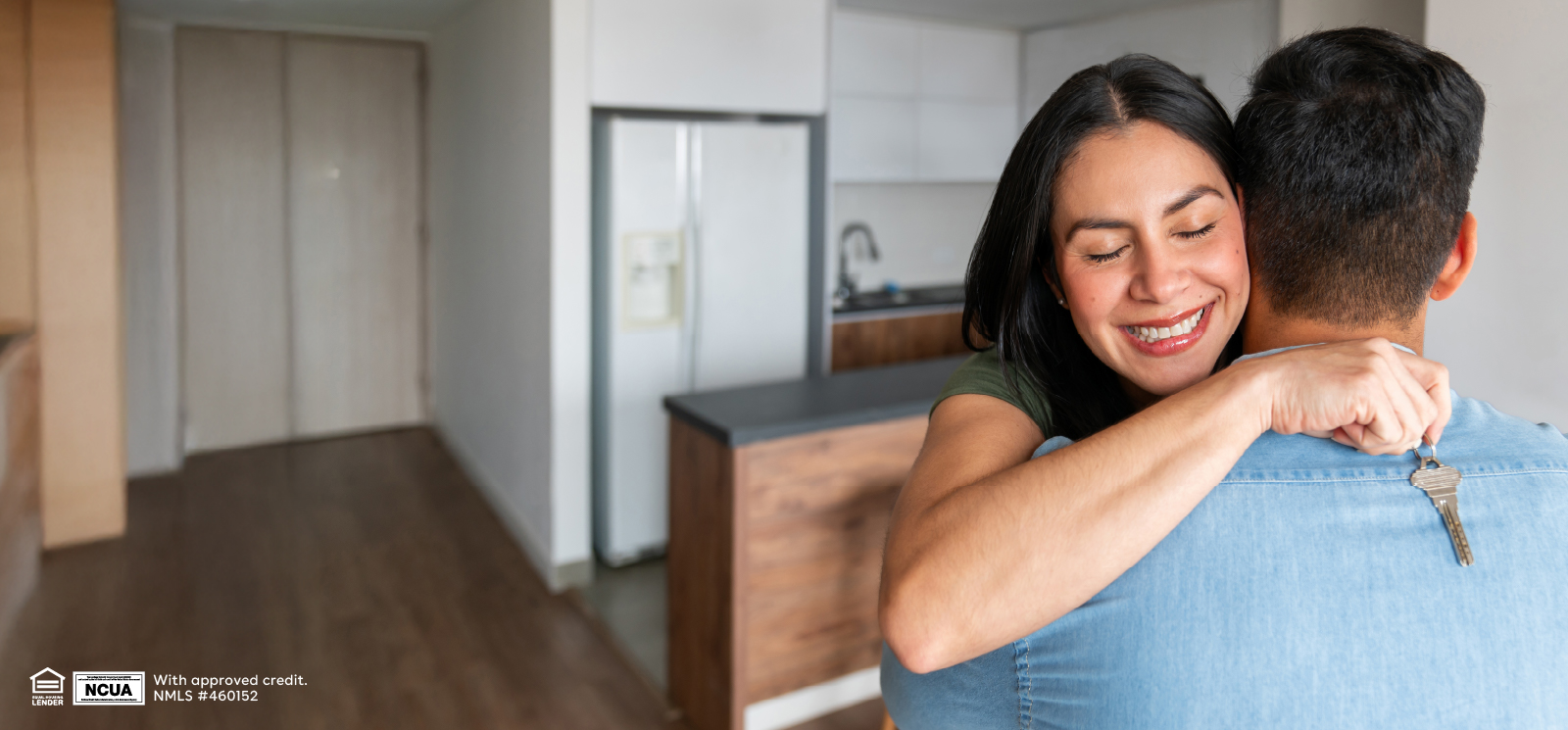 IMAGE: Woman holding keys and hugging partner inside new home