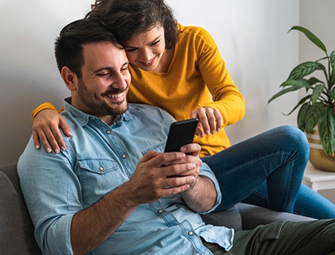IMAGE: Man and woman on couch looking at his mobile phone