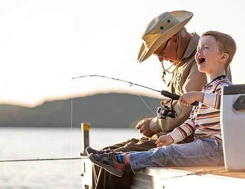 IMAGE: grandfather and grandson fishing on a dock.
