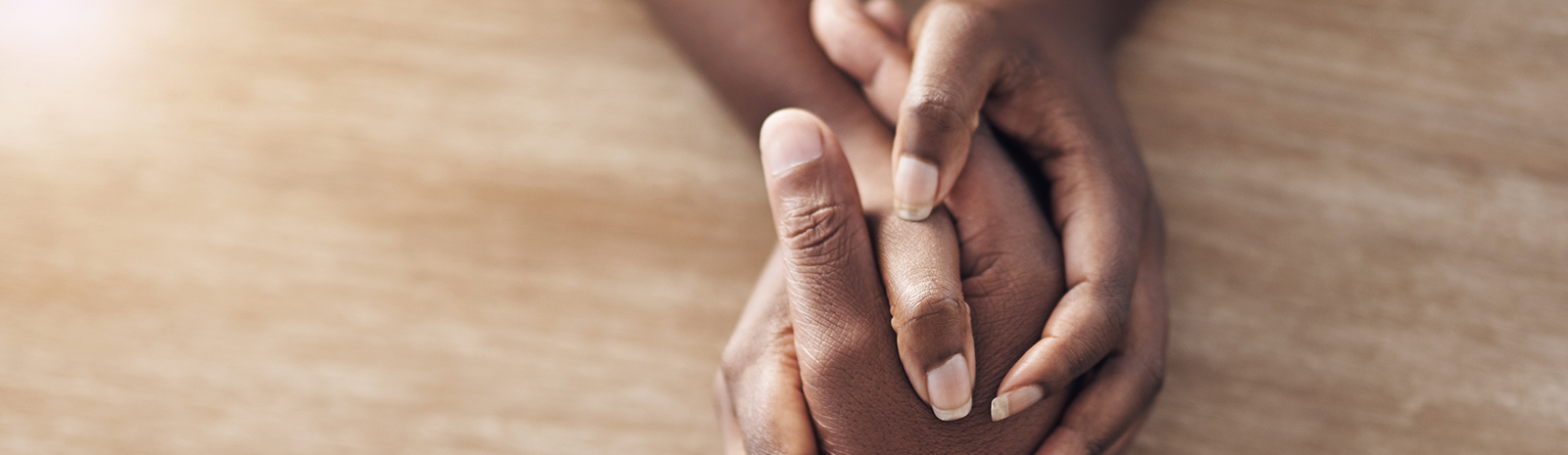 IMAGE: Close-up of two people holding hands across a table