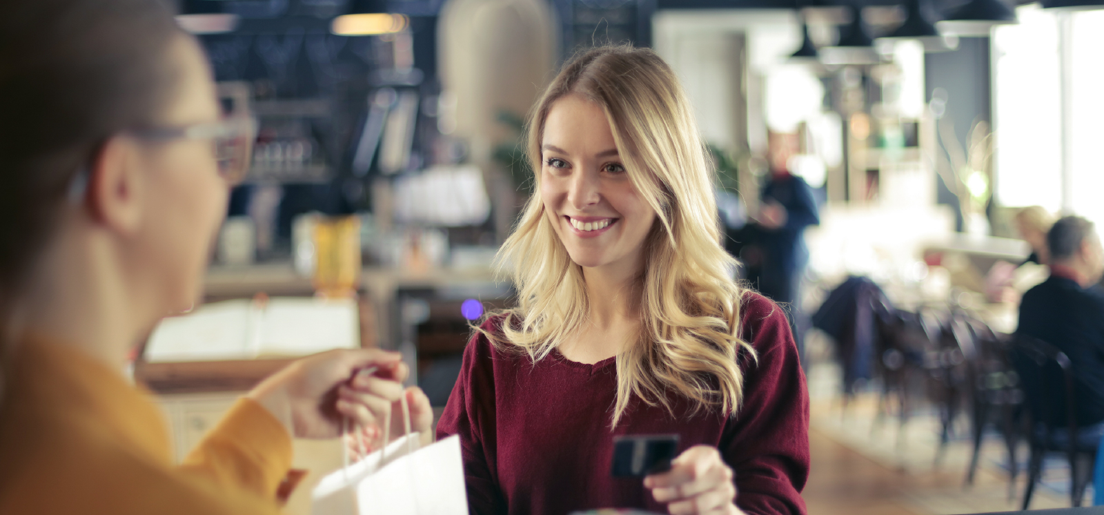 IMAGE: Woman smiling while using credit card to shop