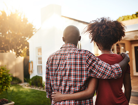 IMAGE: Backs of a couple standing in front of a house