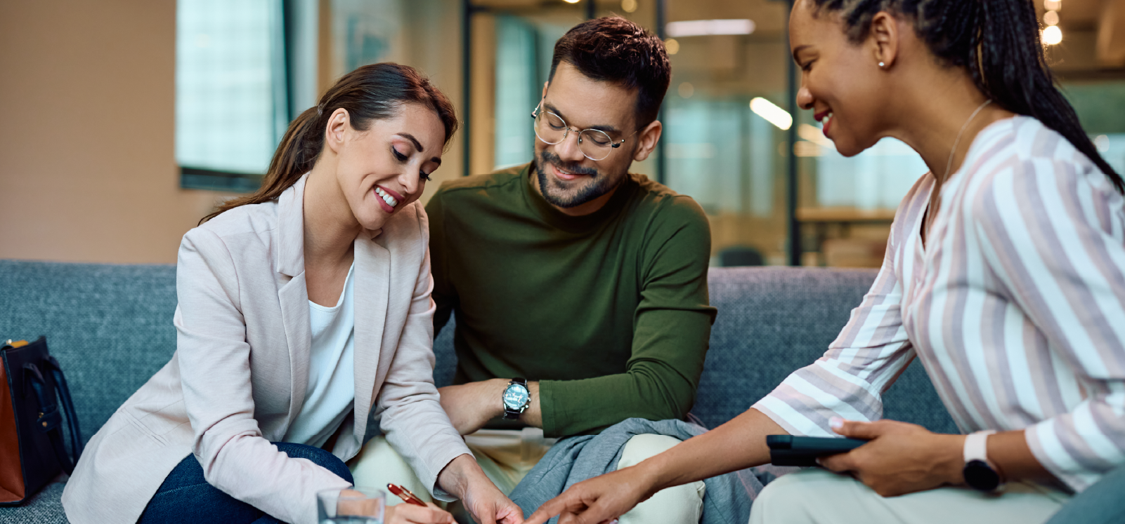 IMAGE: Couple smiling while signing paperwork inside an office