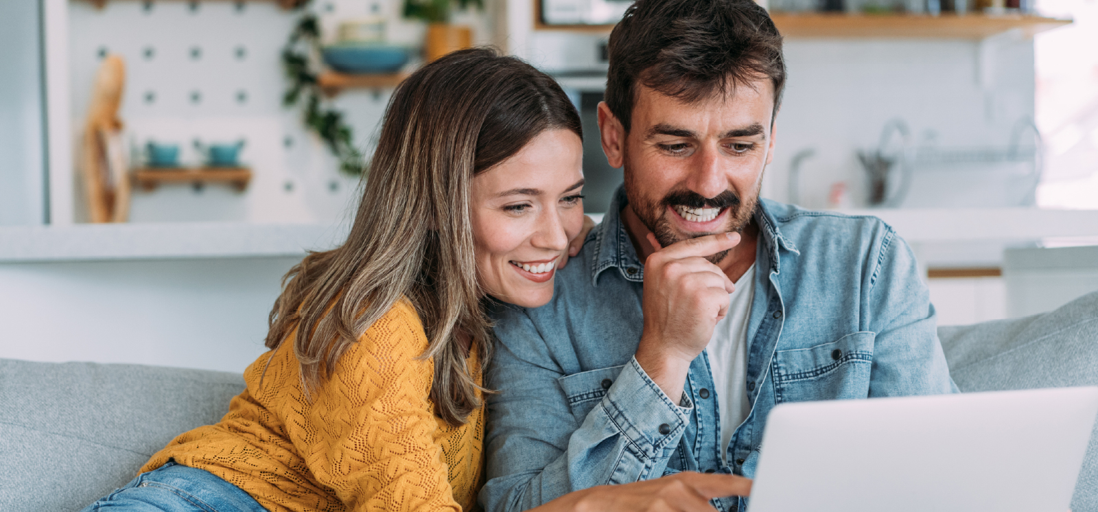 IMAGE: Couple sitting on a couch looking at a laptop