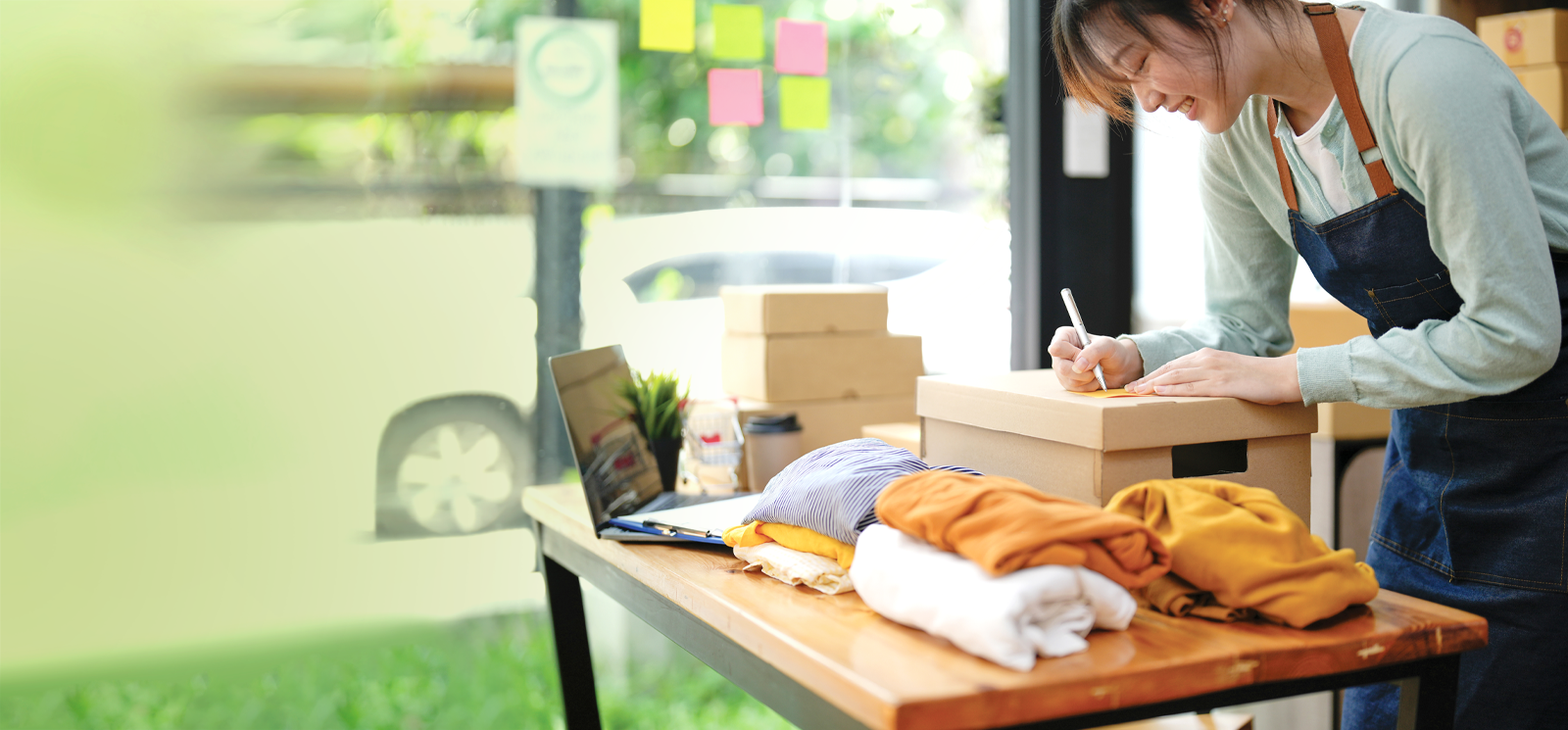 IMAGE: Woman in a clothing shop writing on a box