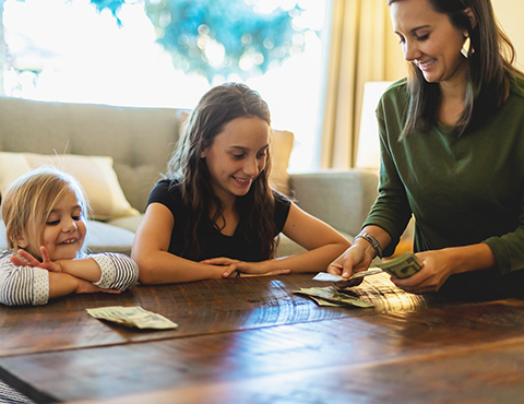 IMAGE: woman counting dollars while two young daughters watch
