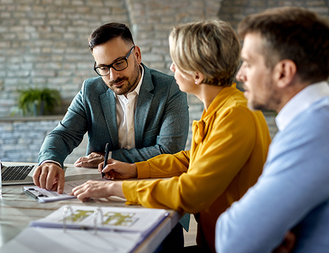 IMAGE: Couple talking with real estate agent and signing paperwork