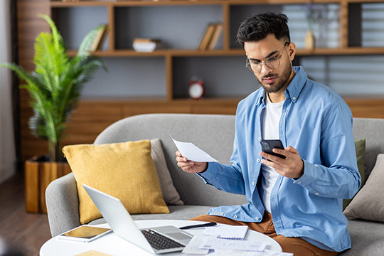IMAGE: Man holding phone and paper looking concerned