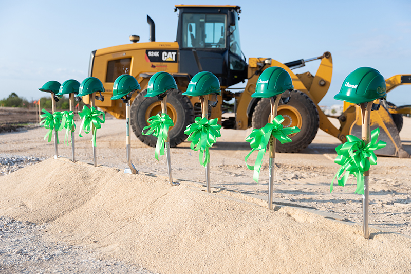 IMAGE: Shovels in ground with hard hats on top and front end loader in background at HQ groundbreaking ceremony