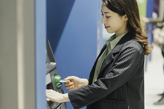 IMAGE: Woman at outdoor ATM inserting card