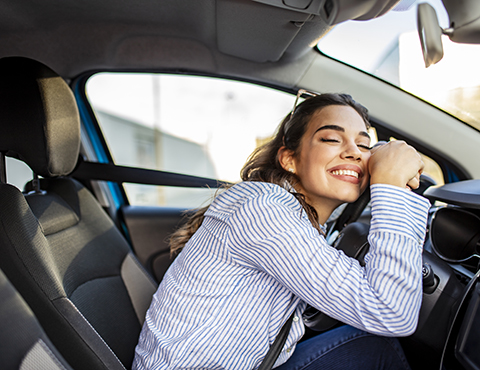 IMAGE: Girl in drivers seat hugging steering wheel