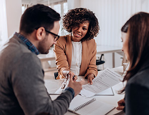 IMAGE: Couple signing paperwork with agent