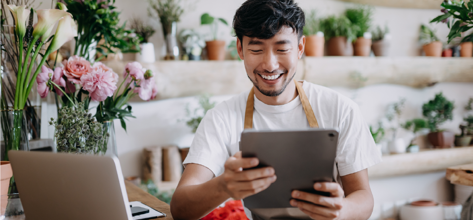 IMAGE: Employee in flower shop smiling while using tablet