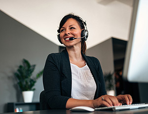 IMAGE: Smiling woman with headset working on computer