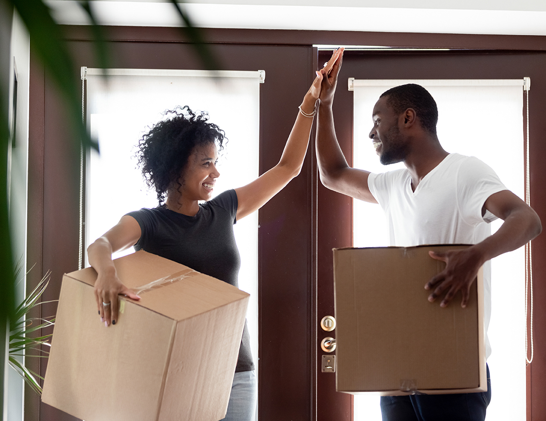 IMAGE: Couple holding boxes inside house and giving each other a high five.