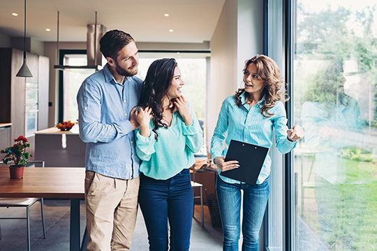 IMAGE: Couple talking with realtor inside home