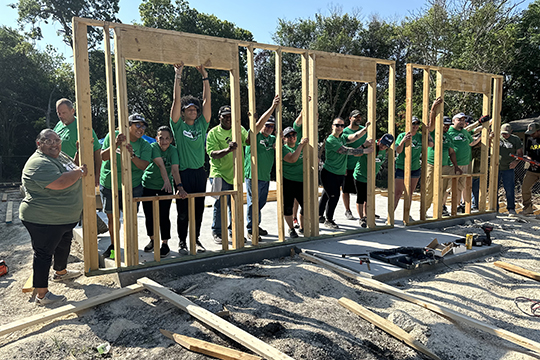 IMAGE: Texell employees holding up framing for wall at Habitat for Humanity Texell Serves event