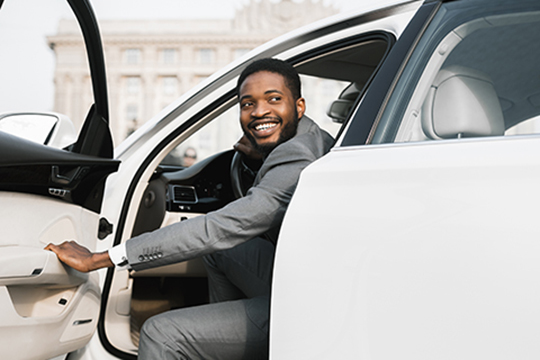 IMAGE: Man smiling while getting into a brand new car.