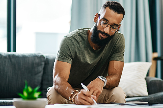 IMAGE: Man sitting at a coffee table writing on paper