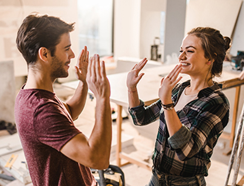 IMAGE: Young couple working on home renovations giving each other high fives