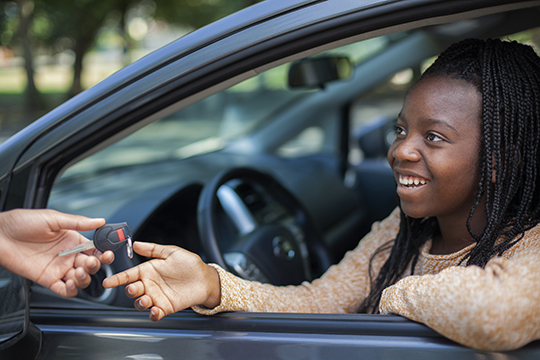 IMAGE: Smiling teen driver behind the wheel of a car being handed keys