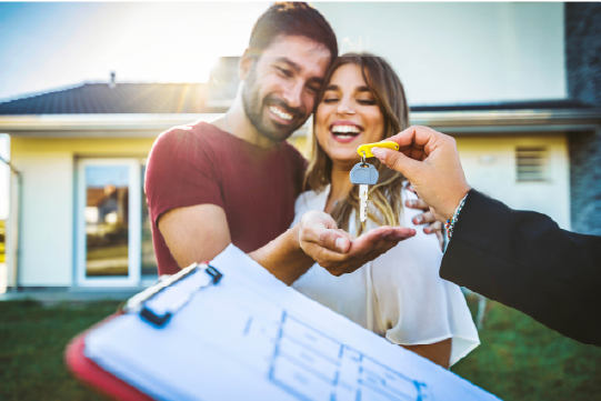 IMAGE: Couple being handed keys and smiling in front of home