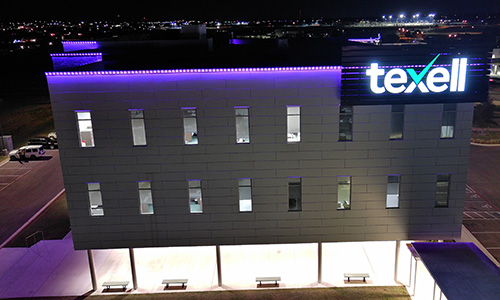 IMAGE: Texell headquarters at night with purple lights along the roof line